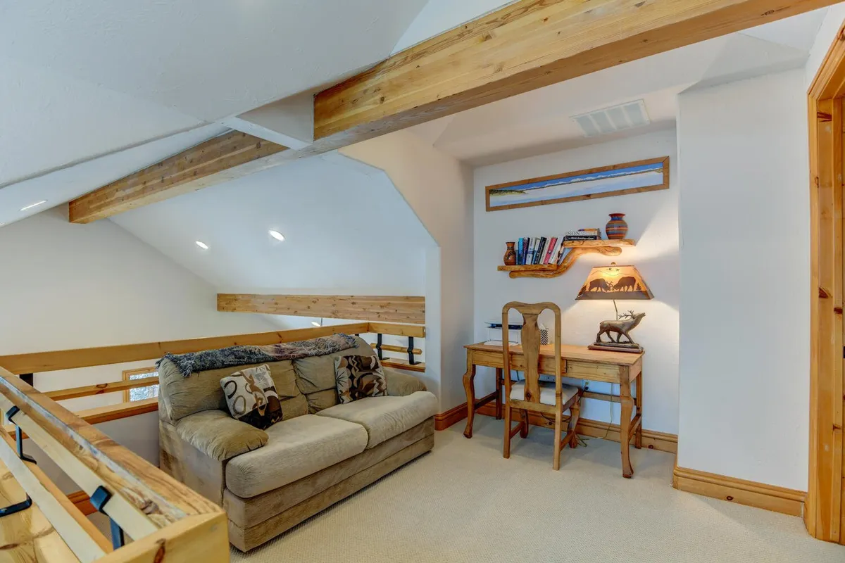 A serene nook featuring a comfortable sofa, desk, bookshelf, and lamp, offering a multi-purpose space for reading, relaxing, or creative work. The atmosphere is calm and welcoming.