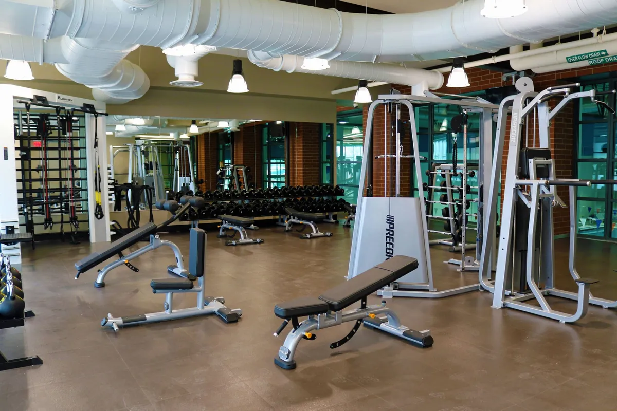 An interior shot of a well-equipped fitness center with weightlifting benches, a dumbbell rack, and cardio machines. The space is bright and motivational, inviting guests to maintain their fitness routines as part of their adventure getaway.